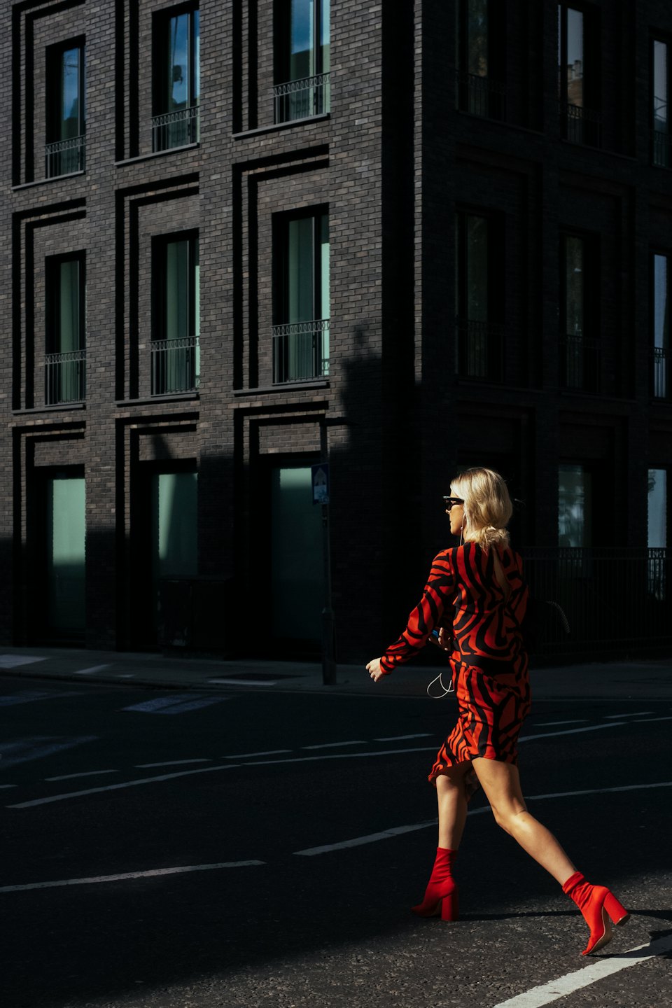 Donna in abito rosso cammina per strada con il telefono.