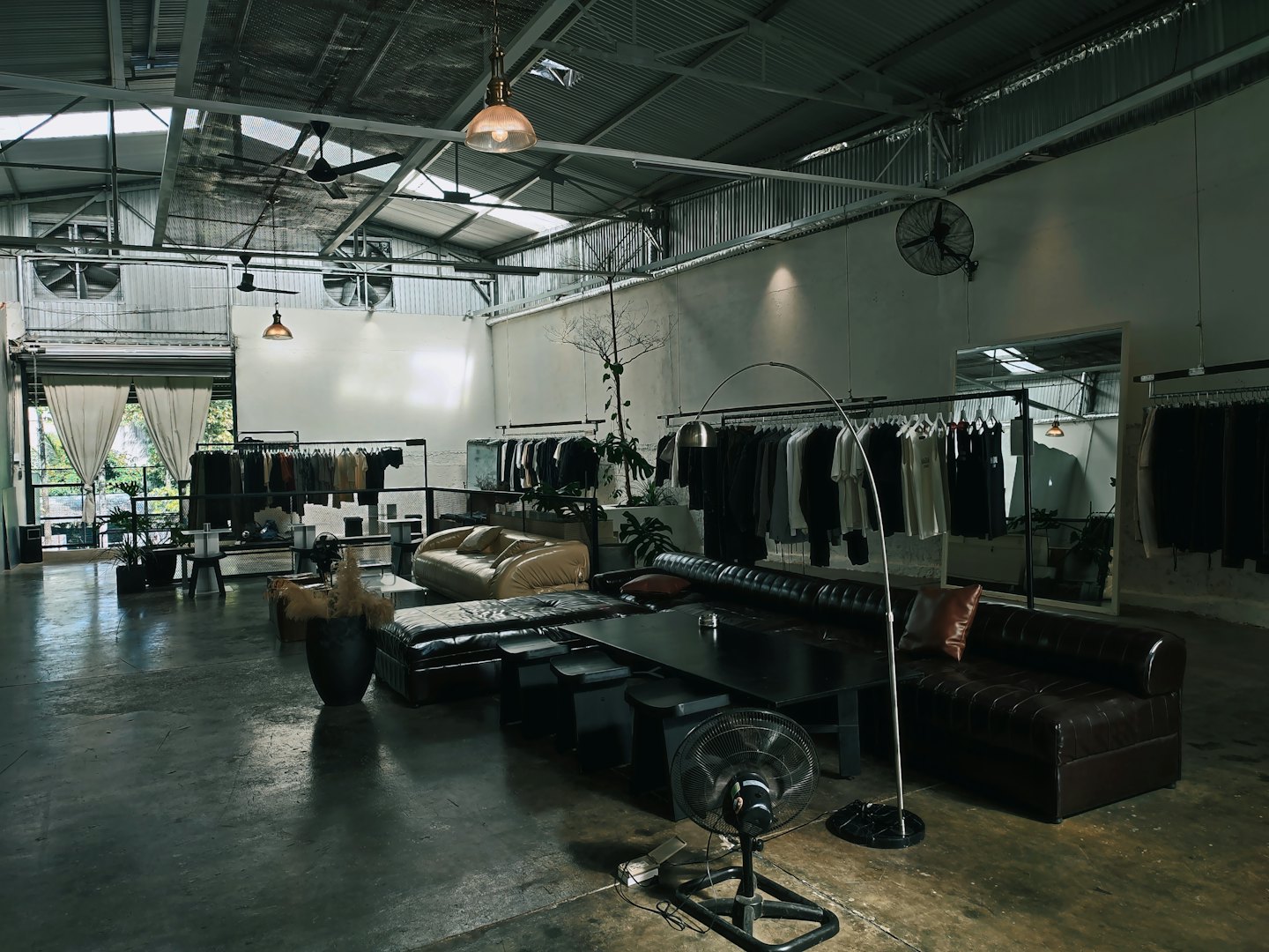 Interno di una boutique moderna con appendiabiti e due divani.