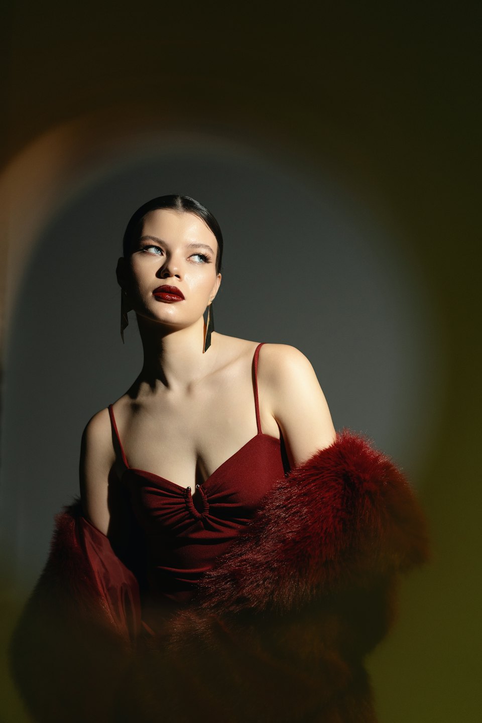 Donna con abito rosso e stola di eco-pelliccia in posa.